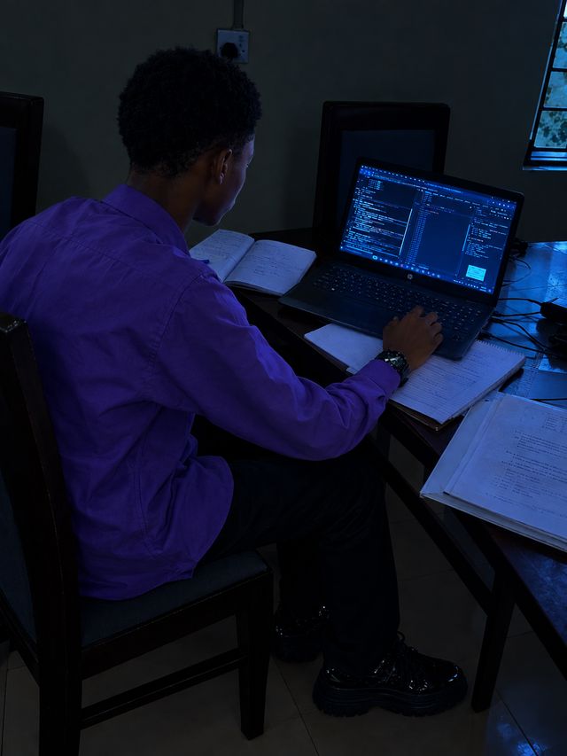 Olasehinde working late, laptop open on a coding project